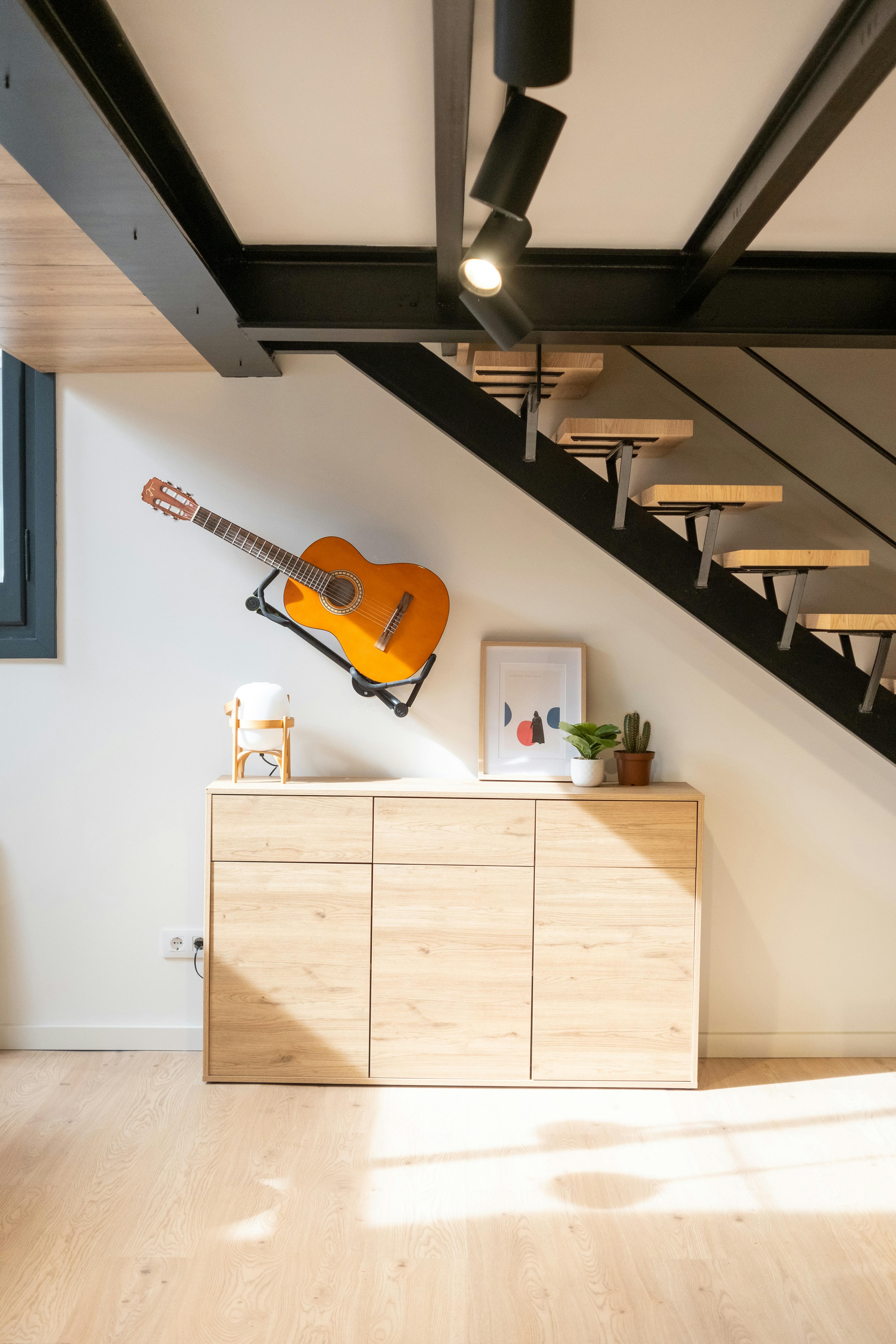 Mueble bajo escalera, con una guitarra colgada